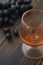 A wineglass of brandy or cognac with a bunch of black grapes Royalty Free Stock Photo