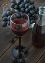 A wineglass of fresh young red wine with glass bottles and a bun Royalty Free Stock Photo