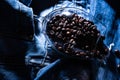 Wineglass full of coffee beans on jeans, close up. Specialty coffee concept. Wineglass with coffee beans overturned