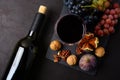 Wineglass with red wine, bottle, grapes, figs and walnuts lying on dark wooden background. Top view. Royalty Free Stock Photo