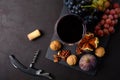 Wineglass with red wine, grapes, figs, walnuts, cork and corkscrew lying on dark wooden background. Top view. Flat lay. Royalty Free Stock Photo