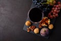 Wineglass with red wine, grapes, figs and walnuts lying on dark wooden background. Top view.