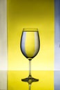 Wineglass with water over grey and yellow background.