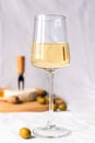 A wineglass of white wine and an olive on the table. In the background in blur a camembert cheese and olives. Selective focus Royalty Free Stock Photo