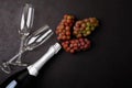 Wineglasses, grapes and bottle of champagne lying on black wooden background. New Year celebration concept. Top view.