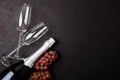 Wineglasses, grapes and bottle of champagne lying on black wooden background. New Year celebration concept. Top view.