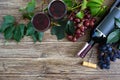 Wineglasses with red wine, bottle, corkscrew, blue grapes, leaves on a wooden table. Wine background with copy space. Top view,