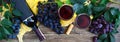 Wineglasses with red wine, bottle, corkscrew, blue grapes, leaves on a wooden table. Wine background with copy space. Top view,