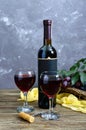 Wineglasses with red wine, bottle, corkscrew, blue grapes, leaves on a wooden table.  Vertical view Royalty Free Stock Photo