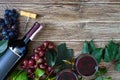 Wineglasses with red wine, bottle, corkscrew, blue grapes, leaves on a wooden table. Wine background with copy space. Top view, Royalty Free Stock Photo