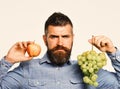 Winegrower with serious face holds grapes and red fruit. Royalty Free Stock Photo