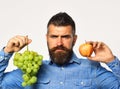 Winegrower with serious face holds grapes and red fruit. Royalty Free Stock Photo