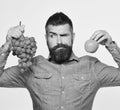 Winegrower with tricky face holds grapes and red fruit. Royalty Free Stock Photo