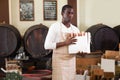 winemaker holding box with wine bottles standing in wine shop