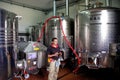 Winemaker standing next to stainless steel fermentation vessels