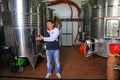 Winemaker standing next to stainless steel fermentation vessels