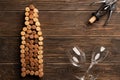 Winery background: bottle shaped corks, corkscrew and two wine glasses on wooden table Royalty Free Stock Photo