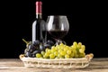 Winery still-life. Varieties of grapes with wineglass and bottle of wine on black background Royalty Free Stock Photo