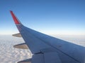 Wing aircraft flying in the sky. The tip of the wing is red. The top of the plane is the blue sky and the bottom is a white cloud. Royalty Free Stock Photo