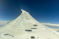 Wing of aircraft soaring above the clouds on a clear day with a deep blue sky Royalty Free Stock Photo