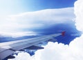 Wing of airplain flying over the white clouds with blue sky.