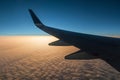 Wing of airplane above clouds at sunset Royalty Free Stock Photo