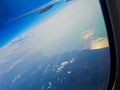 The wing of an airplane against clear blue sky and white clouds above the sea. Horizontal photo, travel concept Royalty Free Stock Photo