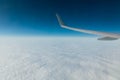 wing of an airplane in flight above clouds in a blue sky Royalty Free Stock Photo