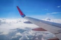 Wing of airplane flying above the clouds in the blue sky background through the window. Royalty Free Stock Photo