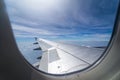 Wing of airplane flying above the clouds in the blue sky background through the window. Royalty Free Stock Photo