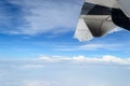 Wing of airplane flying above the clouds and blue sky Royalty Free Stock Photo