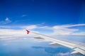 Wing of airplane flying above the clouds in the blue sky Royalty Free Stock Photo