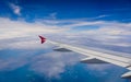 Wing of airplane flying above the clouds in the blue sky Royalty Free Stock Photo