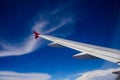 Wing of airplane flying above the clouds in the blue sky Royalty Free Stock Photo