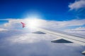 Wing of airplane flying above the clouds in the blue sky Royalty Free Stock Photo