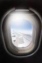 Wing of airplane flying above the clouds in the blue sky background through the window. Royalty Free Stock Photo