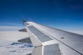 Wing of airplane flying above the clouds in the blue sky background through the window. Royalty Free Stock Photo