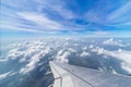 Wing of airplane flying above the clouds in the blue sky background through the window. Royalty Free Stock Photo