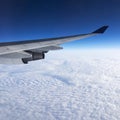 Wing of airplane flying above the clouds in the sky Royalty Free Stock Photo