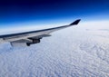 Wing of airplane flying above the clouds in the sky. Royalty Free Stock Photo