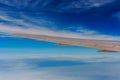 Wing of airplane flying above the clouds in the sky Royalty Free Stock Photo
