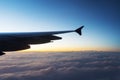 Wing of airplane flying above the clouds in sky with sunset Royalty Free Stock Photo