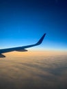 Wing of an airplane flying above the clouds in the sky at sunset Royalty Free Stock Photo