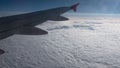 Wing of airplane flying above clouds in the sky and with a view thick clouds under sunny rays. Royalty Free Stock Photo