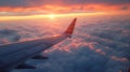 Wing of an airplane flying above the clouds at sunset, view from the window. Travel concept Royalty Free Stock Photo