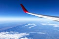 Wing of an airplane flying above the morning clouds and Andean mountain range Royalty Free Stock Photo