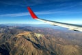 Wing of an airplane flying above the morning clouds and Andean mountain range Royalty Free Stock Photo