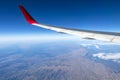 Wing of an airplane flying above the morning clouds and Andean mountain range Royalty Free Stock Photo