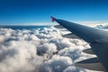 Wing of an airplane flying above the sky with clouds above the ocean Royalty Free Stock Photo