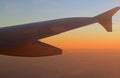 Wing of an airplane flying over the morning clouds in the sky. Sunrise Royalty Free Stock Photo